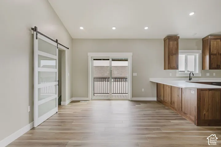 Open-concept living space featuring wood-finish flooring, recessed lighting, and a sliding glass door leading to an exterior balcony with black iron railings