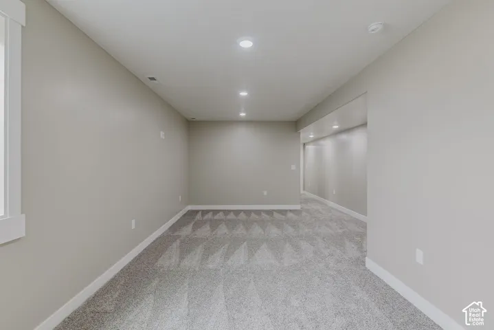 Spacious room featuring neutral paint, recessed lighting, white baseboards, and patterned carpet