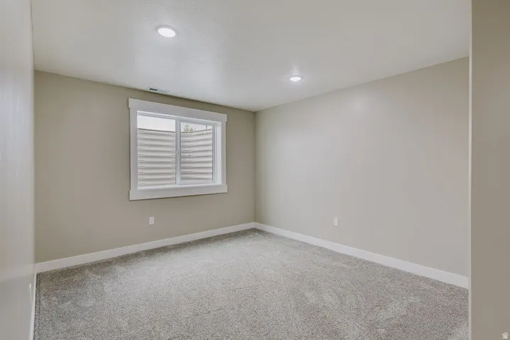 Carpeted room featuring a white-trimmed window, recessed ceiling lights, and light-toned wall paint