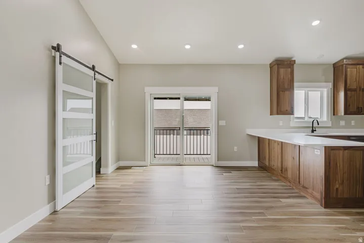 Open-concept living space featuring wood-finish flooring, recessed lighting, and a sliding glass door leading to an exterior balcony with black iron railings