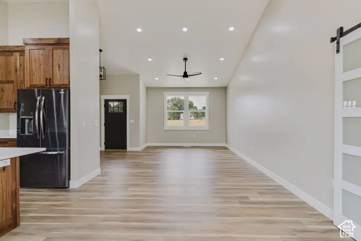 Spacious open-concept living area featuring wood-finish flooring, recessed lighting, and a modern ceiling fan