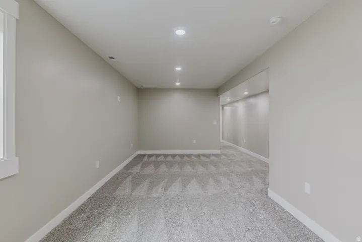 Spacious room featuring neutral paint, recessed lighting, white baseboards, and patterned carpet