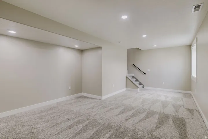 Spacious room featuring neutral-toned walls, recessed lighting, and patterned carpeting