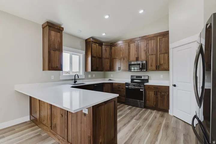 Kitchen featuring extensive wood cabinetry, white countertops, stainless steel appliances, and wood-finish flooring