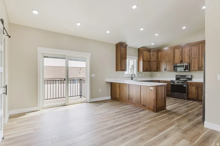 Open-concept kitchen and living area featuring wood-finish flooring, recessed lighting, and a modern kitchen with wood cabinetry
