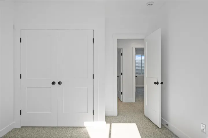 White panel doors with matte black hardware, light neutral carpeting, and white baseboards