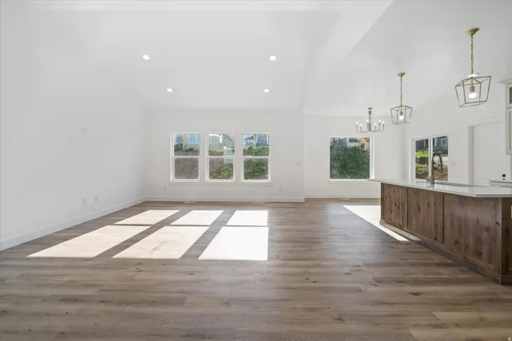 Open-concept living area featuring high vaulted ceilings, recessed lighting, and wood-finish flooring