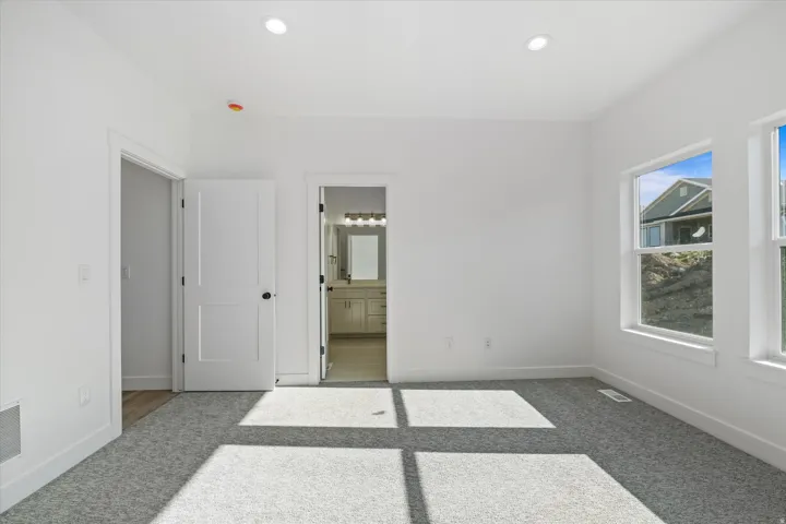 Spacious room with white walls and light gray carpeting