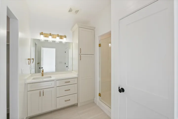 Bathroom featuring a single vanity with stone countertop, undermount sink, and gold-tone faucet