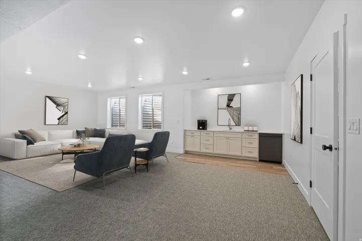 AI Generated Staging. Spacious room featuring recessed lighting, a built-in wet bar with cabinetry, sink, and under-counter refrigerator, and two windows with horizontal blinds
