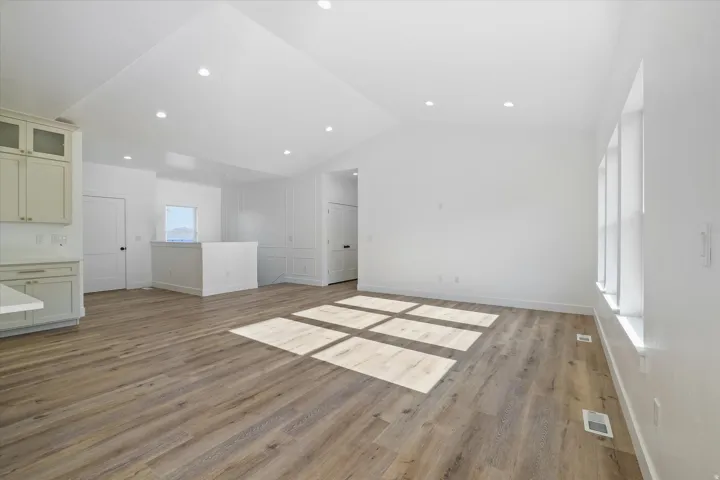 Spacious interior featuring wood-finish flooring, vaulted ceilings with recessed lighting, and bright white walls