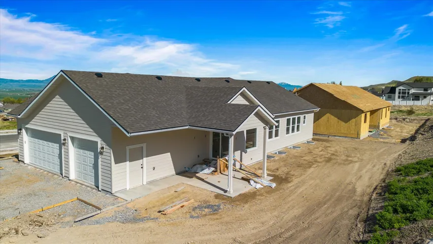 New construction residence featuring light gray siding, a dark shingled roof, and a two-car garage with panel doors