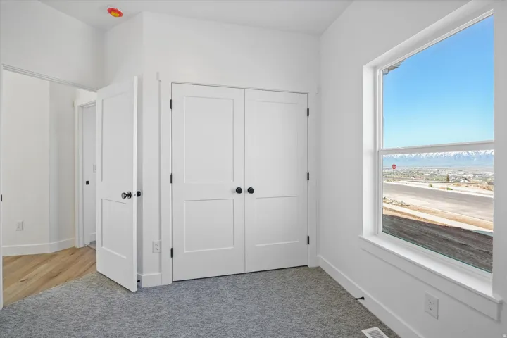 Bedroom featuring a large double-hung window, white trim, and a mountain range backdrop
