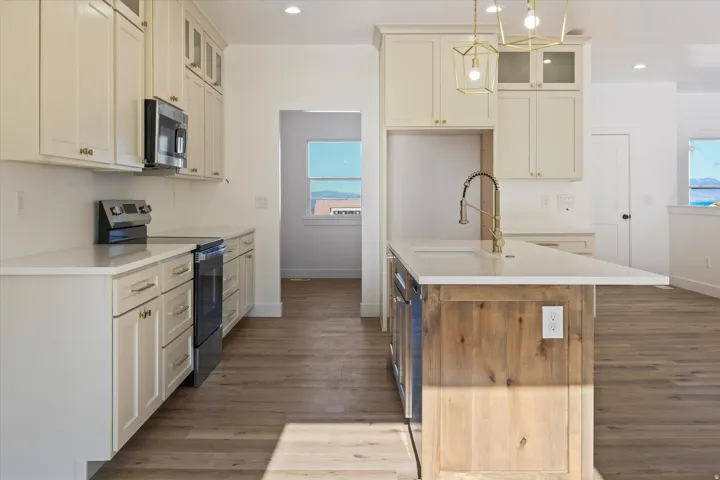 Contemporary kitchen featuring an expansive center island with a wood-finish base, stone countertop, and brass-finish faucet