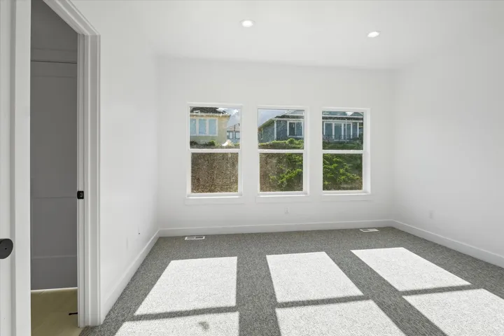 Carpeted room featuring three windows with white trim, recessed lighting, and white walls