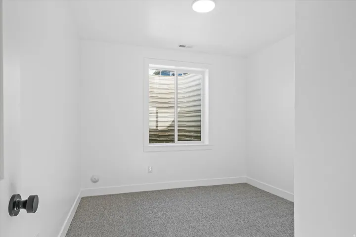 Room featuring neutral wall tones, gray carpeting, and a white-trimmed window