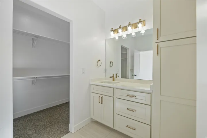 Bathroom vanity with a white countertop, under-mount sink, and gold-tone fixtures