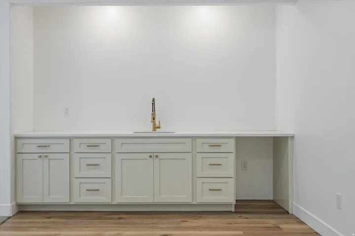 Built-in cabinetry with ample storage, a countertop basin sink, and a modern gold-finish faucet