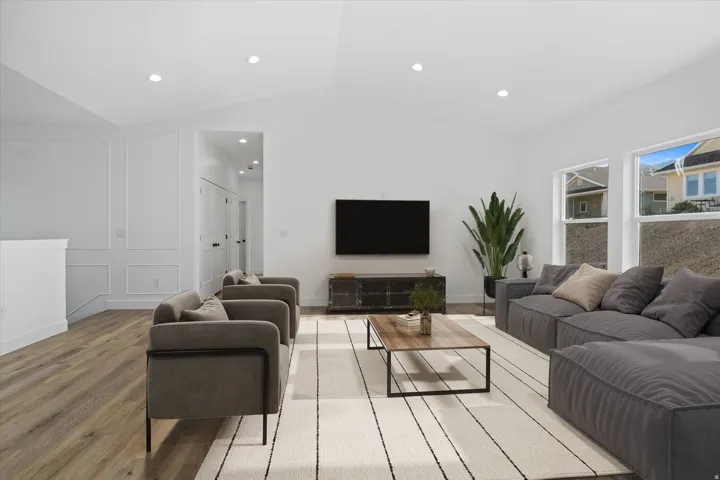 Ai Generated Spacious living area featuring vaulted ceilings, recessed lighting, wood-finish flooring, and white paneled wall detailing