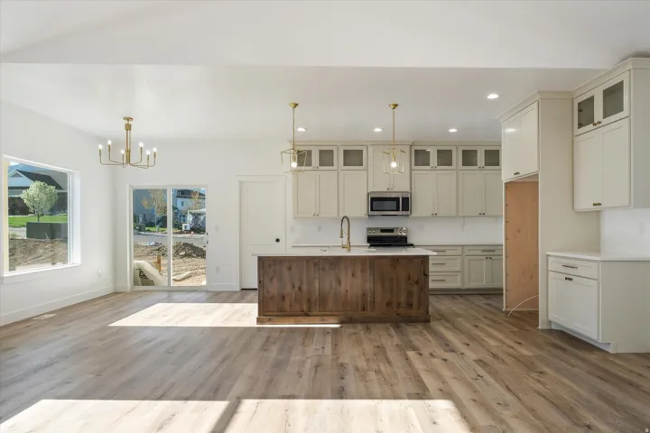Open-concept kitchen and living area featuring wood-finish flooring, recessed lighting, and a sliding glass door