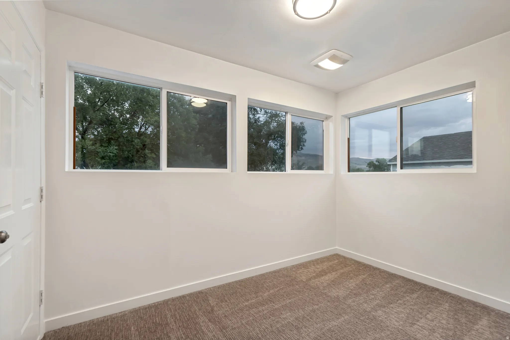 Neutral wall finishes complemented by light-colored carpeting, multiple windows, recessed lighting, and a white interior door