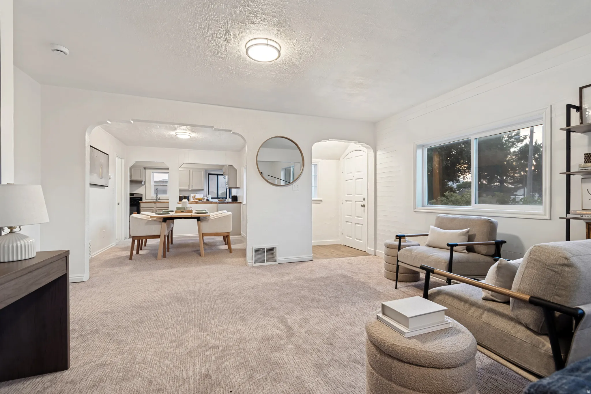 Bright living area featuring light-toned carpeting and a large window