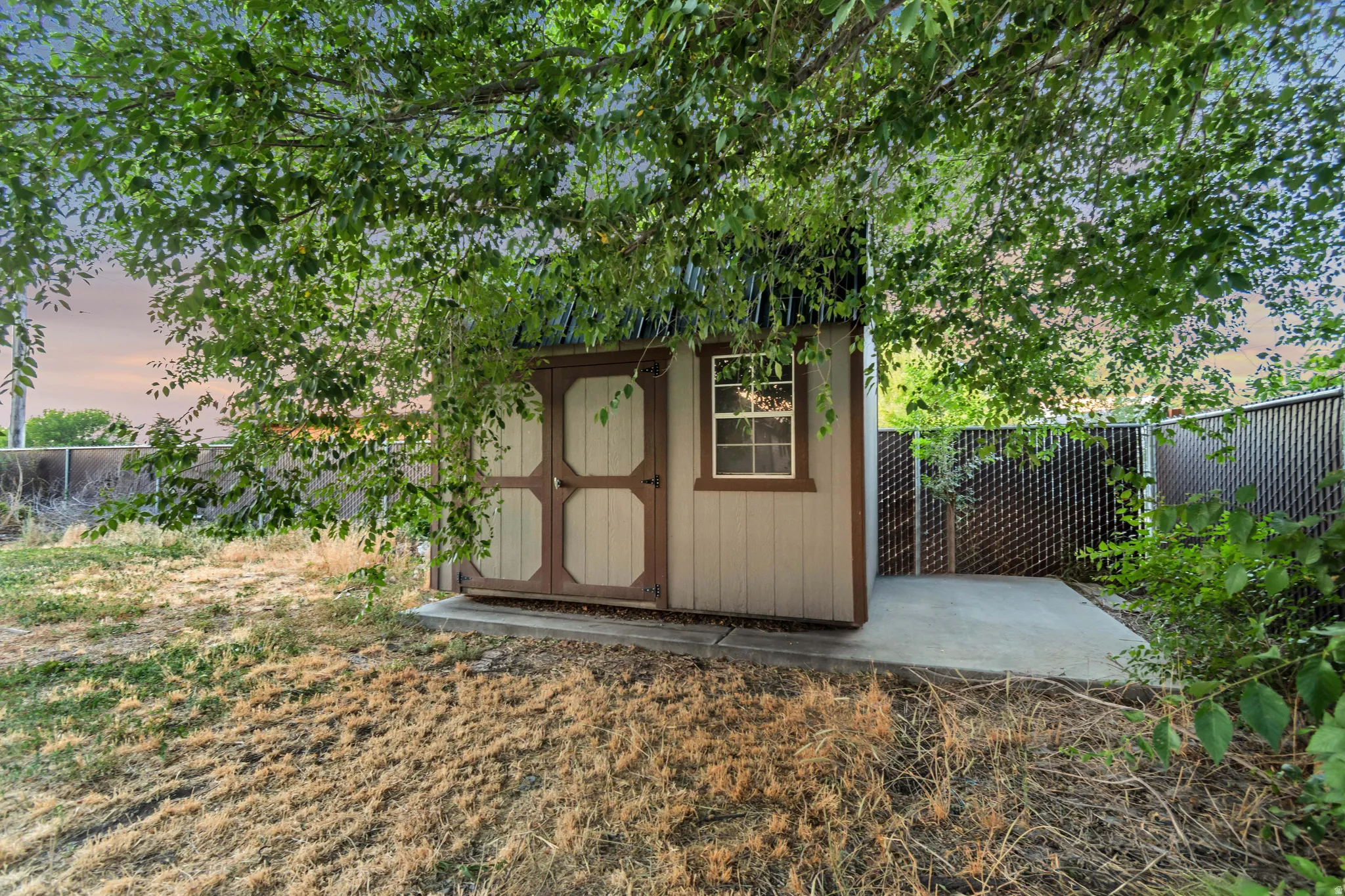 Garden shed featuring a window, double doors, and an attached concrete pad