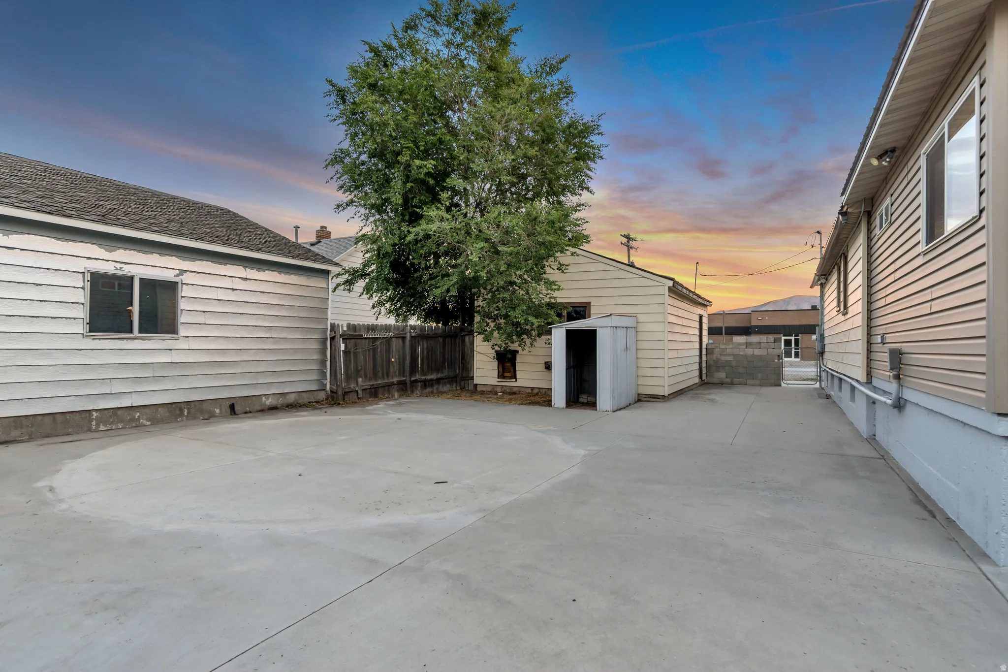 Expansive concrete driveway and patio area, featuring a detached garage with an adjacent storage shed