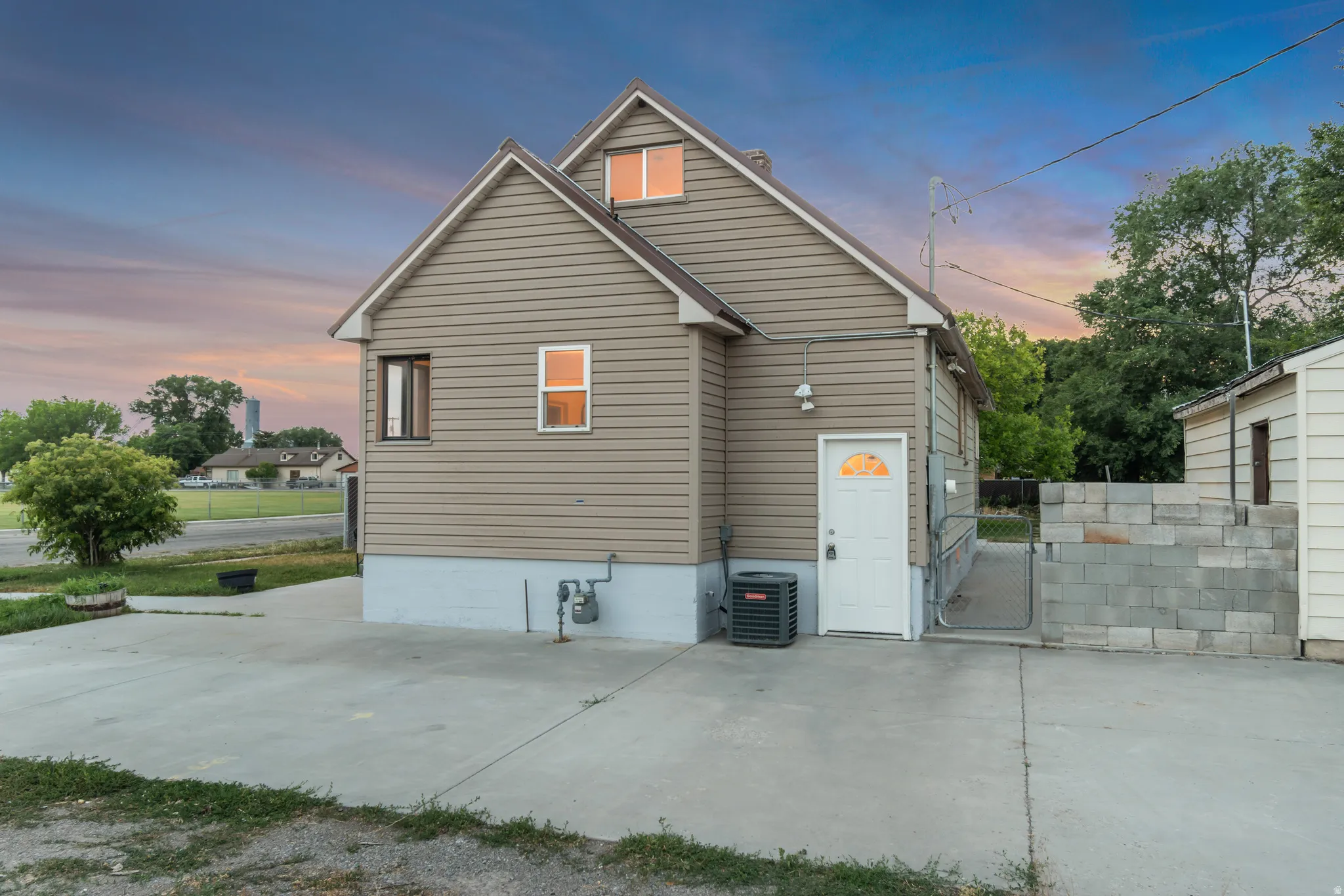 Exterior featuring tan horizontal siding, a gabled roofline, and a concrete driveway