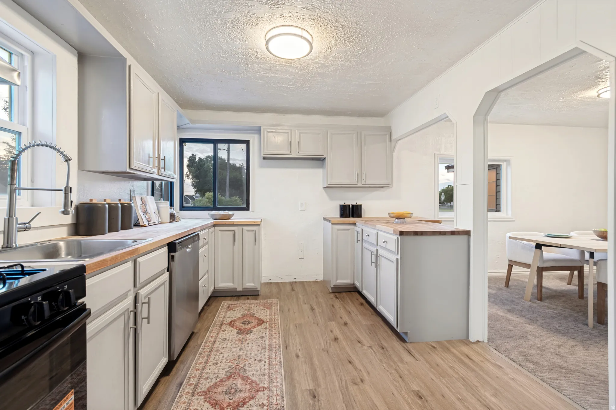 Kitchen featuring light gray cabinetry, wood-finish countertops, stainless steel appliances, and wood-finish flooring
