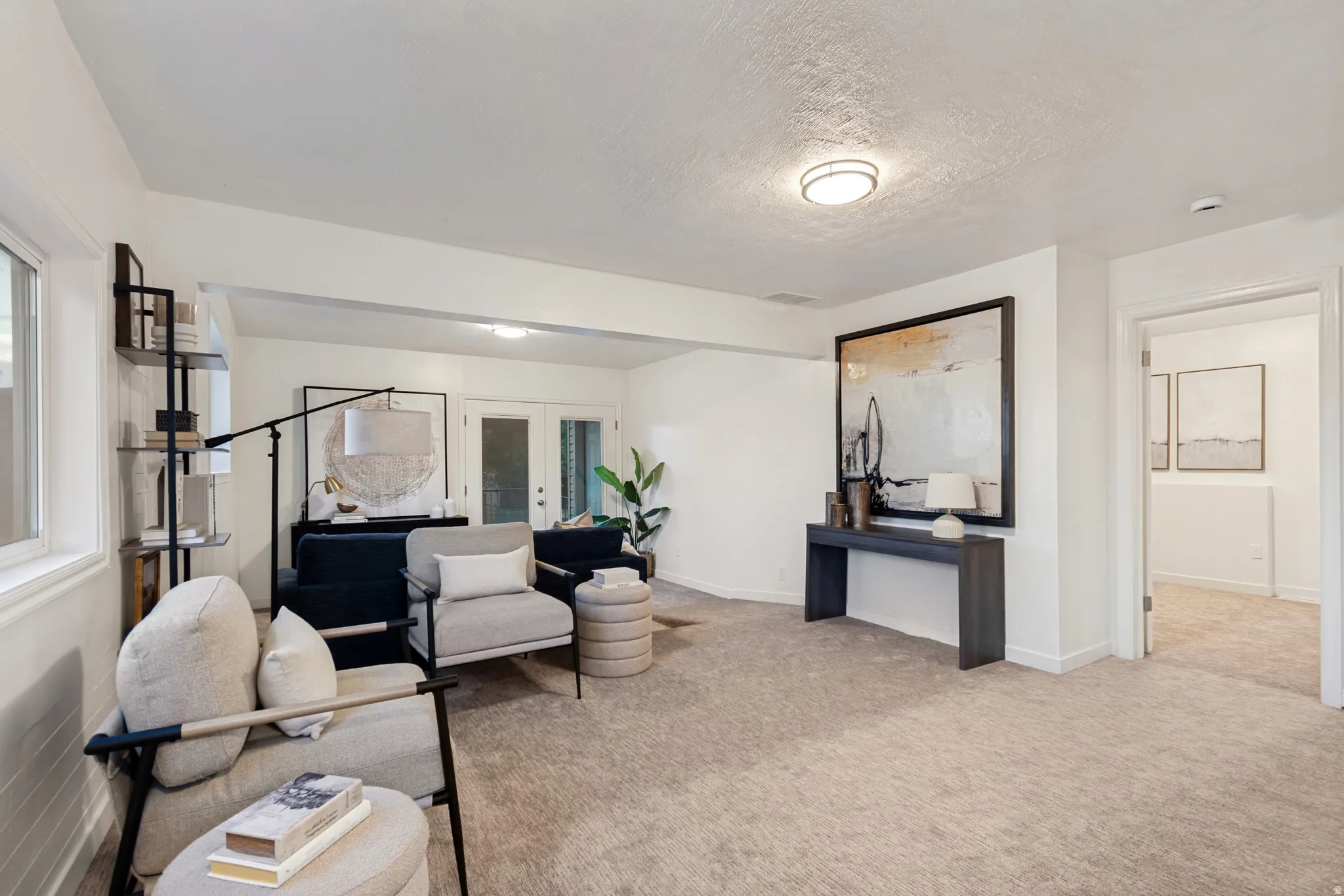 Spacious room featuring neutral carpeting, white walls, recessed lighting, and a window providing natural light