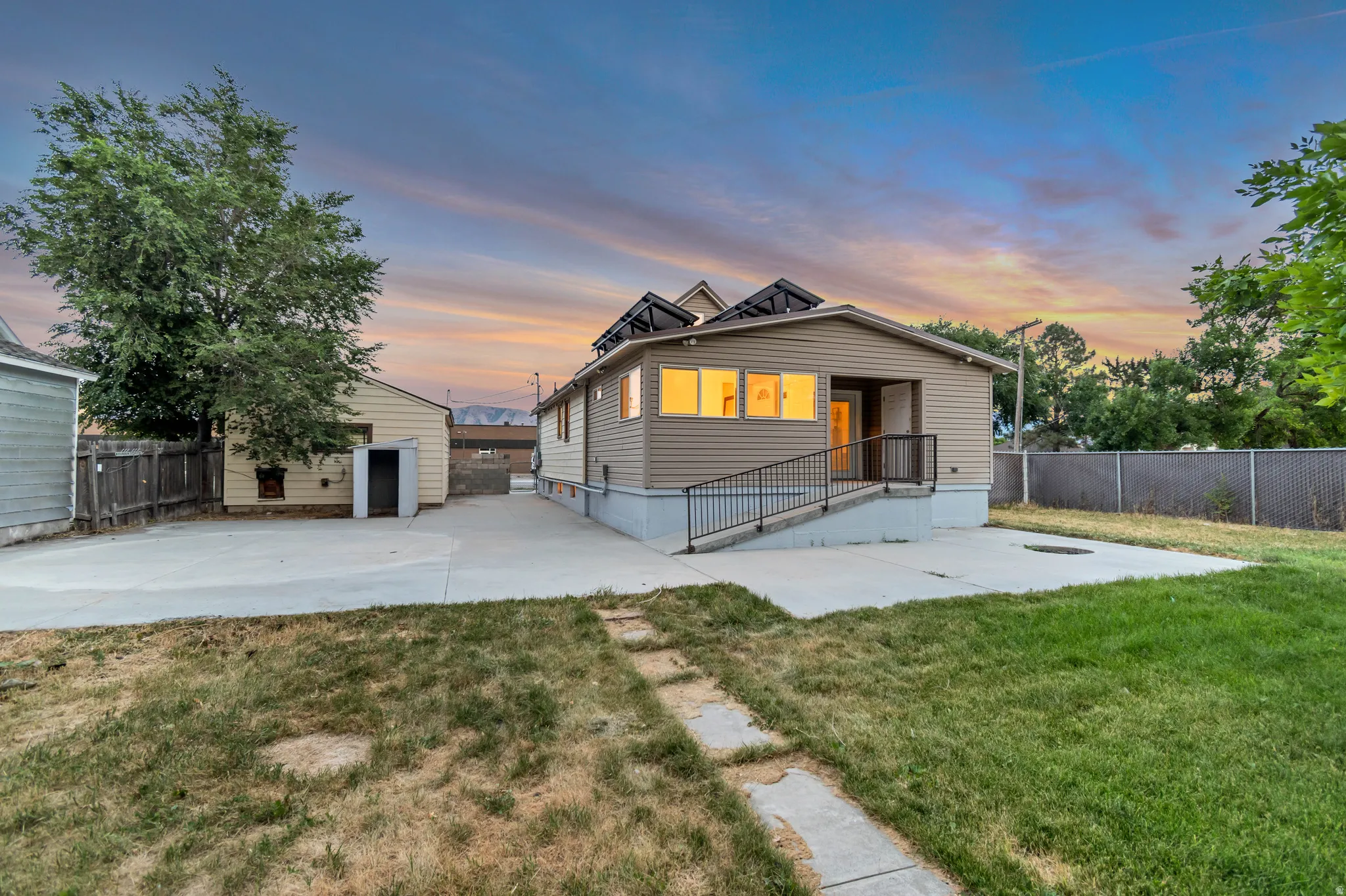 Rear exterior featuring tan siding, a concrete patio, and a grass lawn