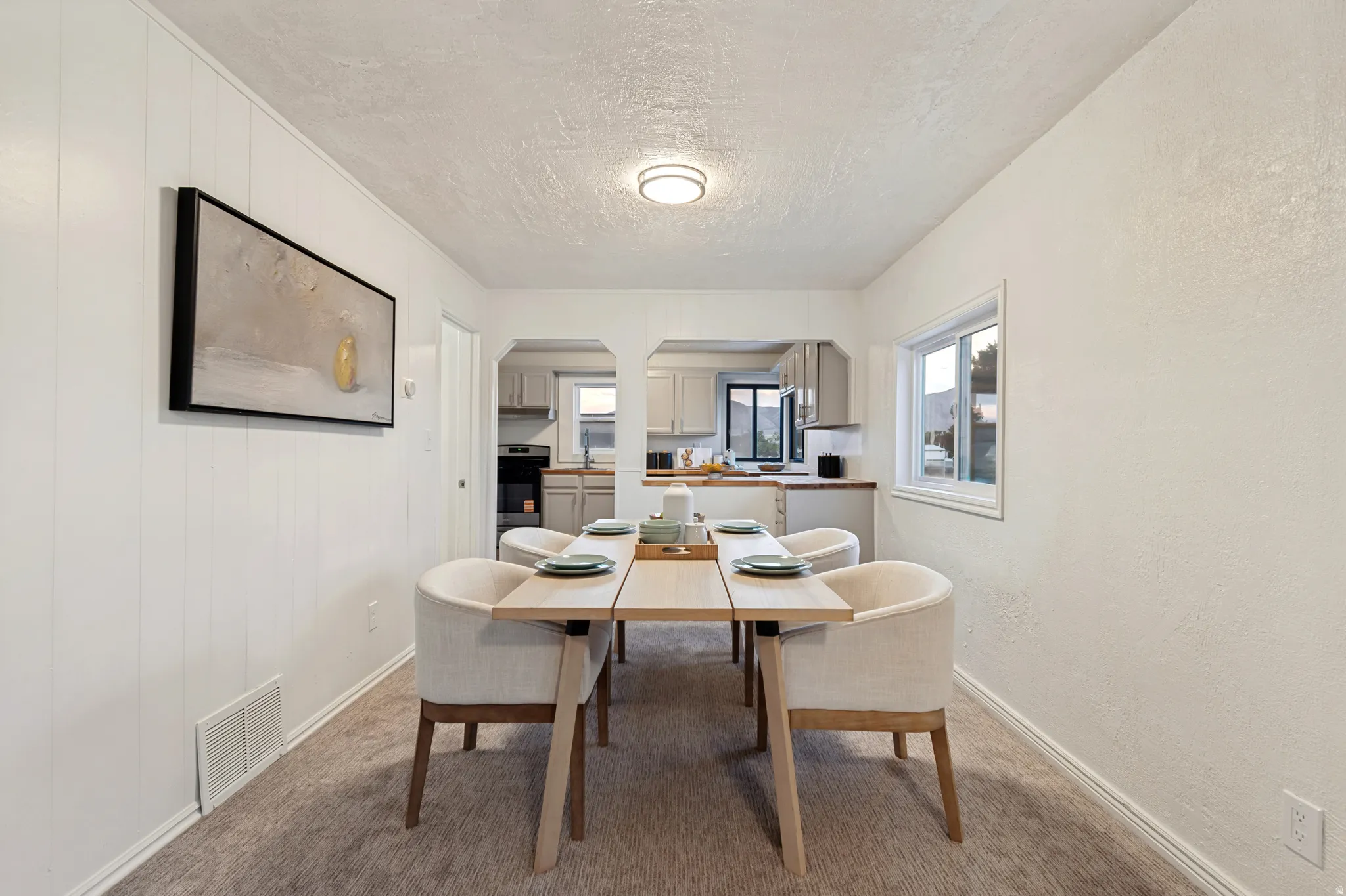 Dining area featuring textured walls, a single window, and carpet flooring