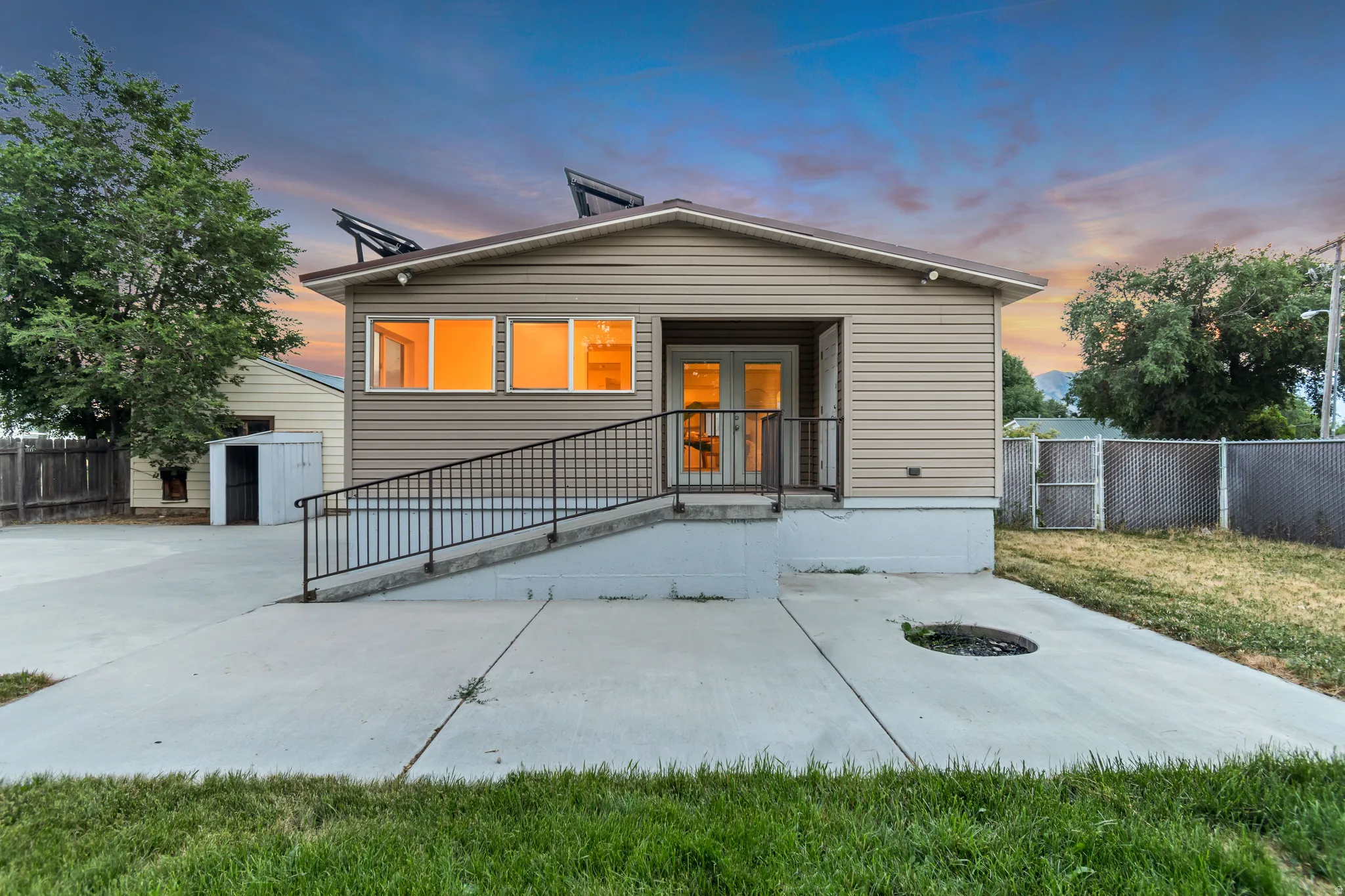 Rear exterior featuring horizontal siding, a concrete patio, and a ramp entrance with black metal railings