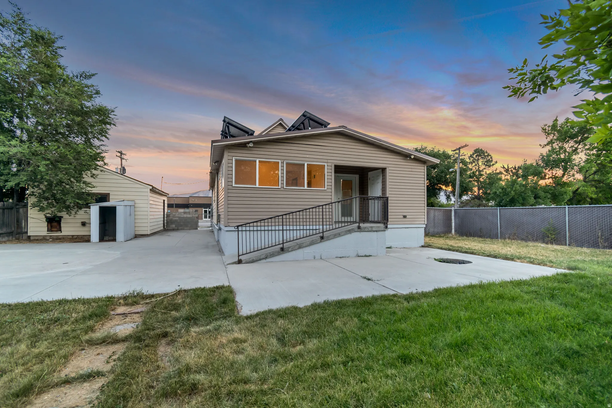 Single-story property with tan vinyl siding, a covered entry, and a concrete ramp with a black metal railing