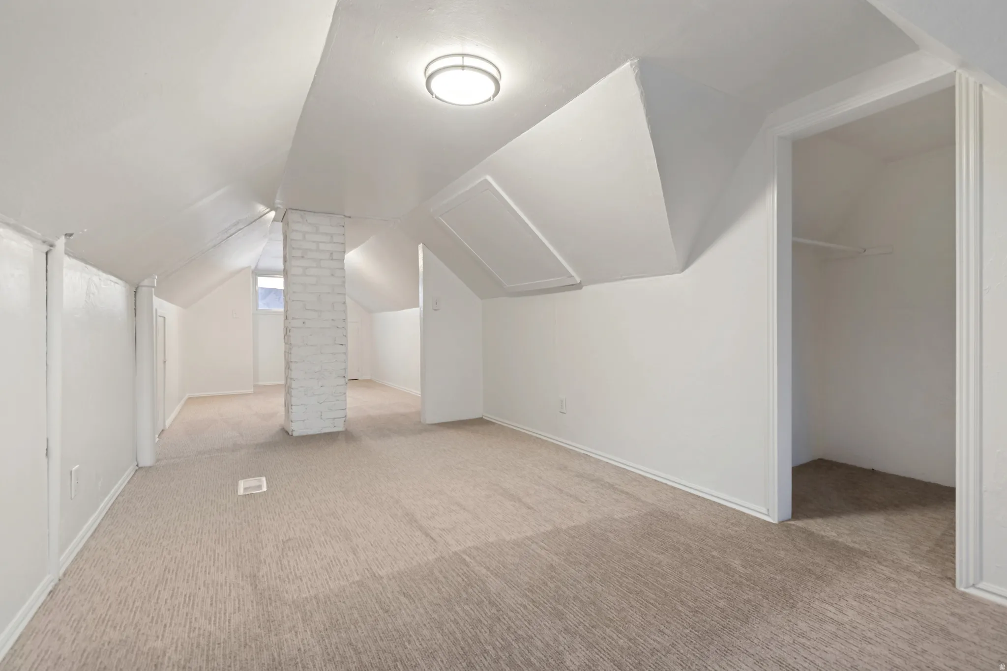 Carpeted room featuring a white brick column, sloped ceilings, and recessed lighting