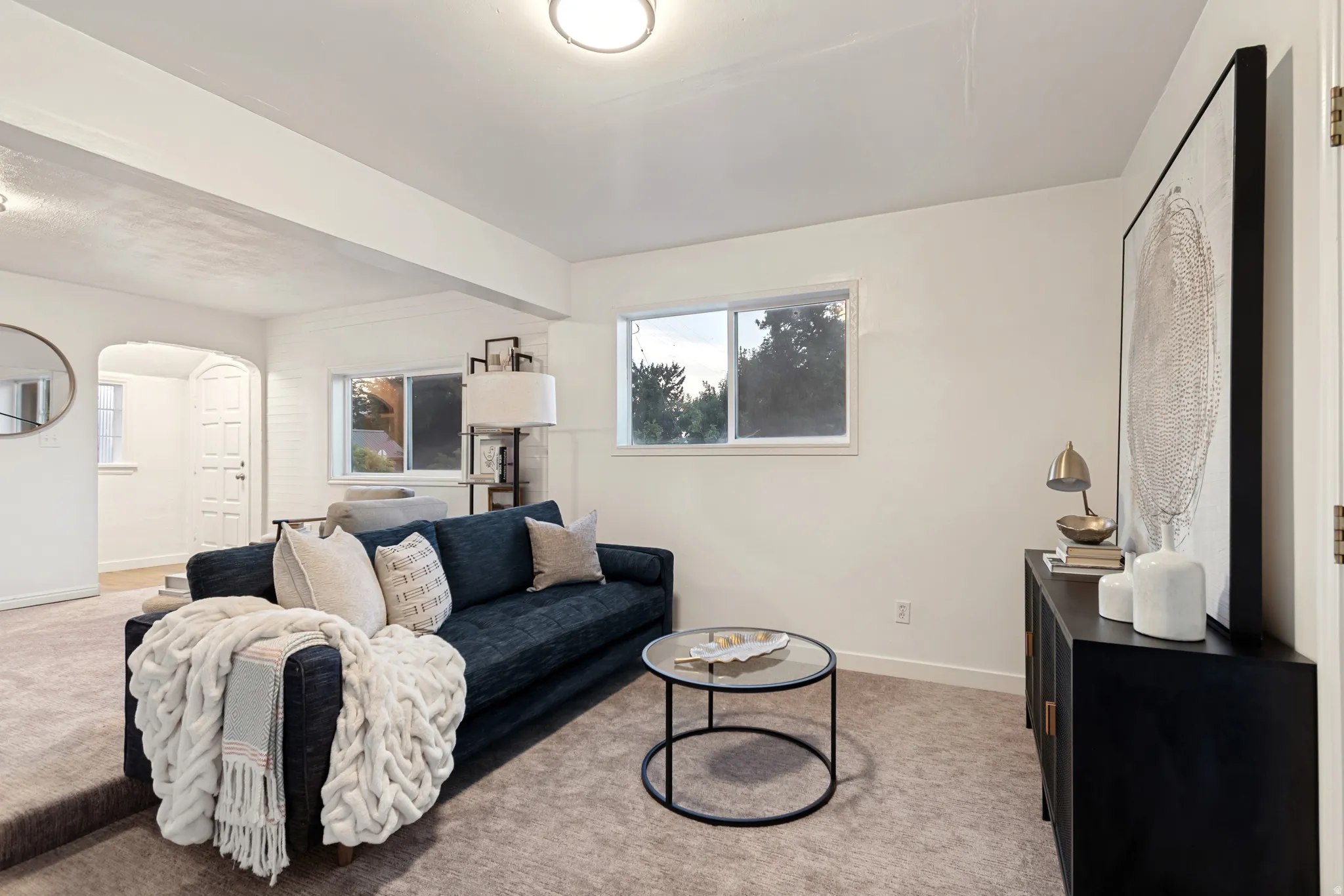 Carpeted living area featuring white walls, recessed lighting, and a window with natural light