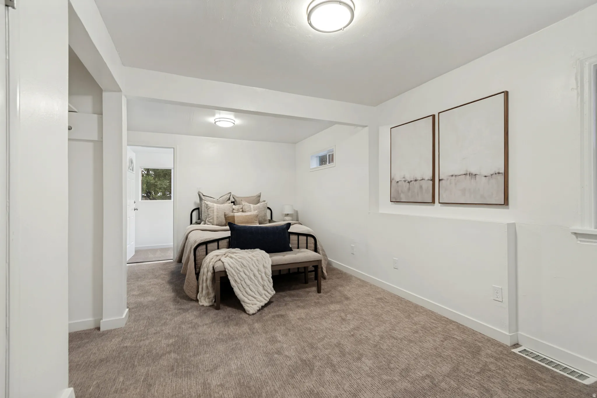 Carpeted room featuring white walls and trim, a white ceiling with flush-mount lighting, and a small window