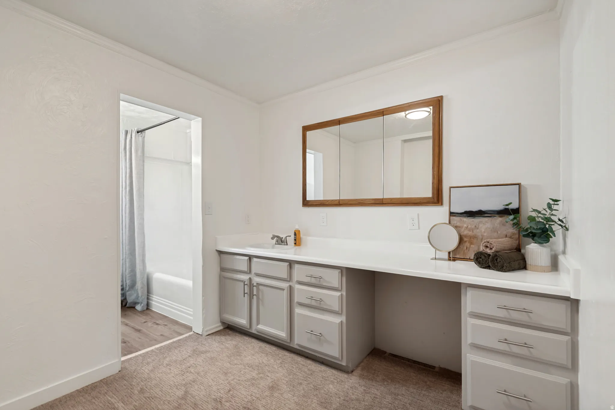 Bathroom vanity featuring a single sink, light-toned countertop, and light-gray cabinetry with brushed nickel hardware
