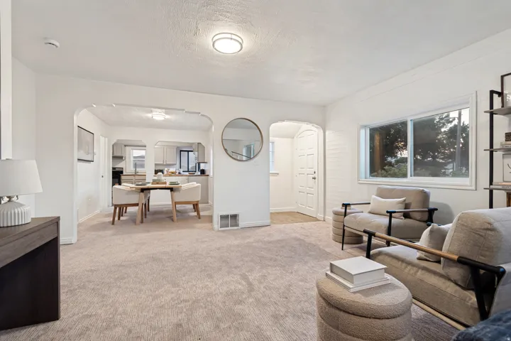 Bright living area featuring light-toned carpeting and a large window