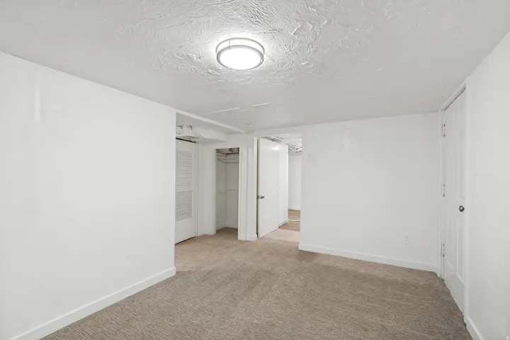 Carpeted room featuring white walls, a textured ceiling, and a flush-mount ceiling light fixture