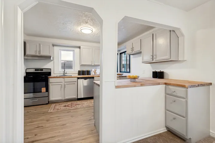 Kitchen featuring light gray cabinetry, wood-finish countertops, stainless steel appliances, and wood-finish flooring