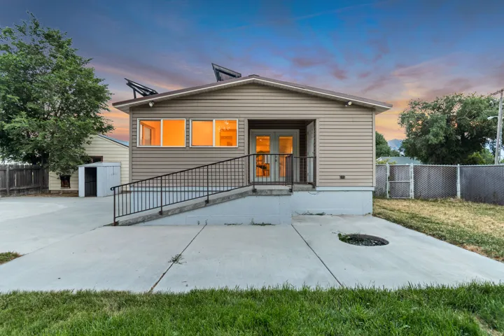 Rear exterior featuring horizontal siding, a concrete patio, and a ramp entrance with black metal railings
