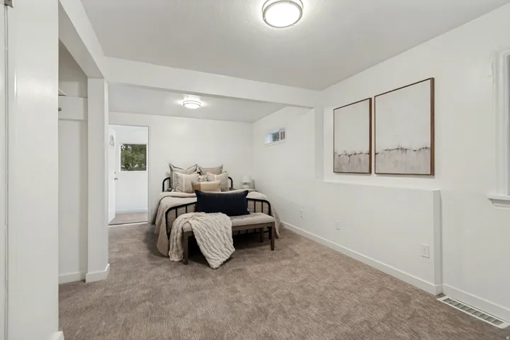 Carpeted room featuring white walls and trim, a white ceiling with flush-mount lighting, and a small window