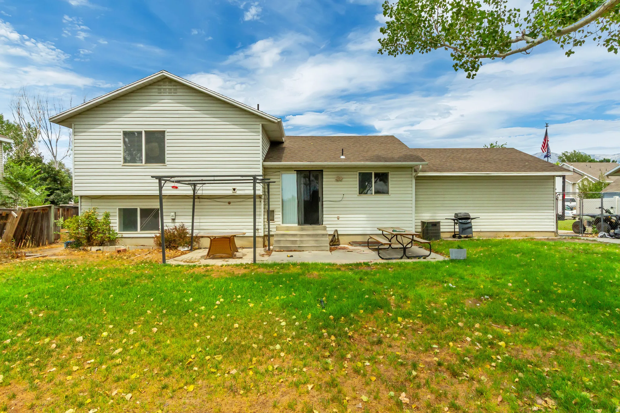 Spacious rear yard featuring a concrete patio, sliding glass door access, and a durable vinyl siding exterior