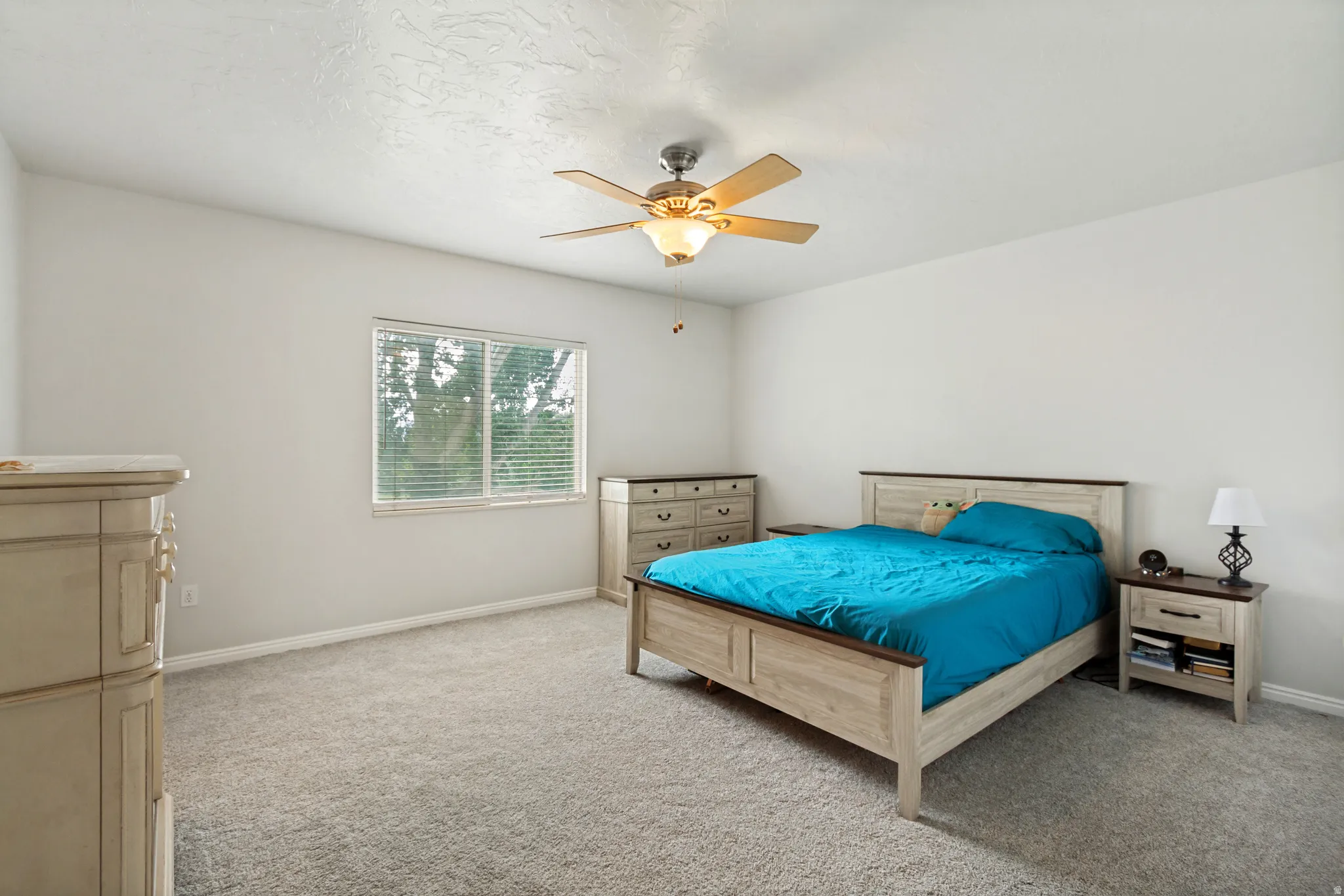 Carpeted room featuring a ceiling fan with integrated lighting, a window with horizontal blinds, and neutral wall tones