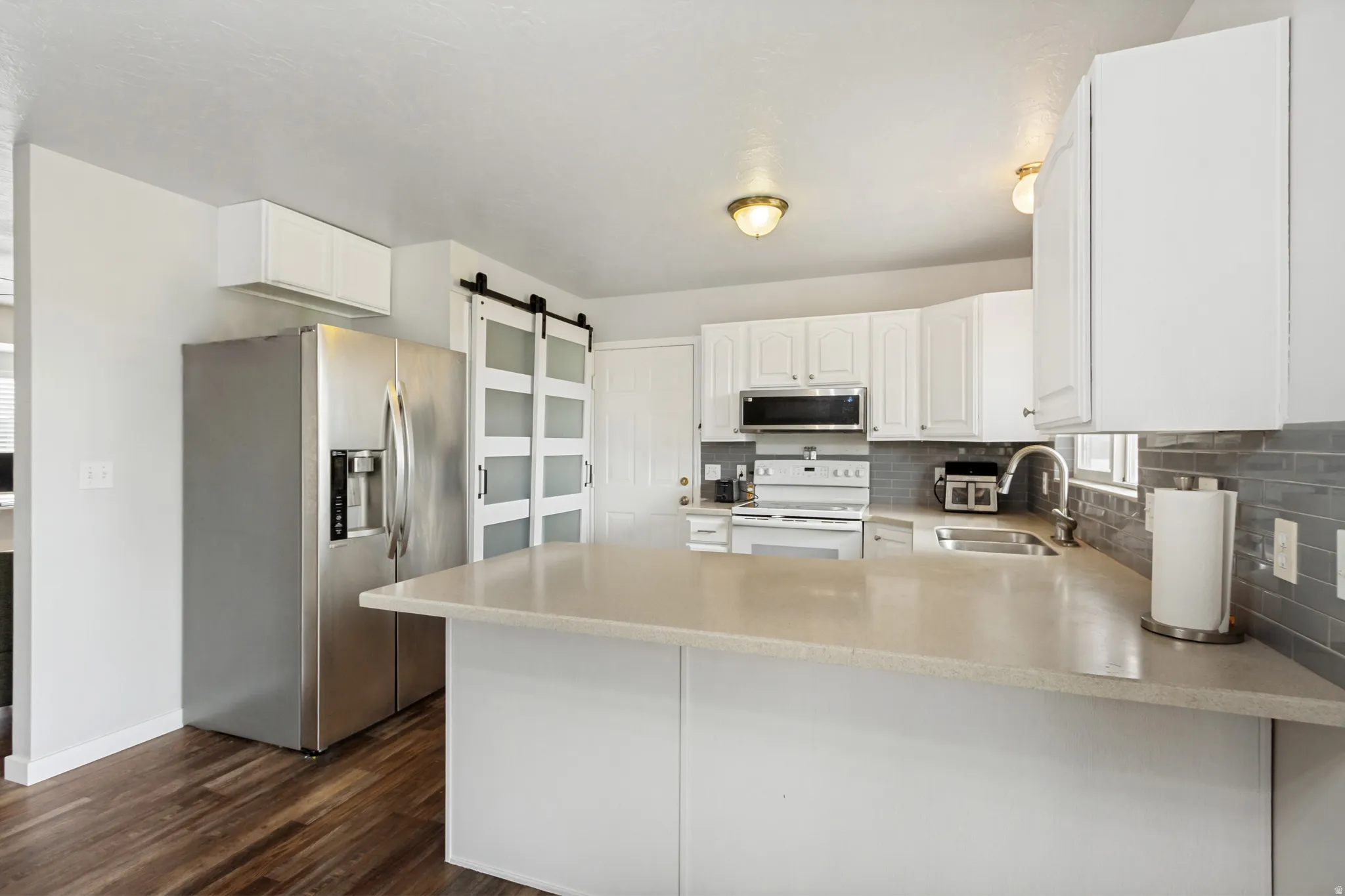 Kitchen featuring an expansive counter-height island, white cabinetry, and wood-finish flooring