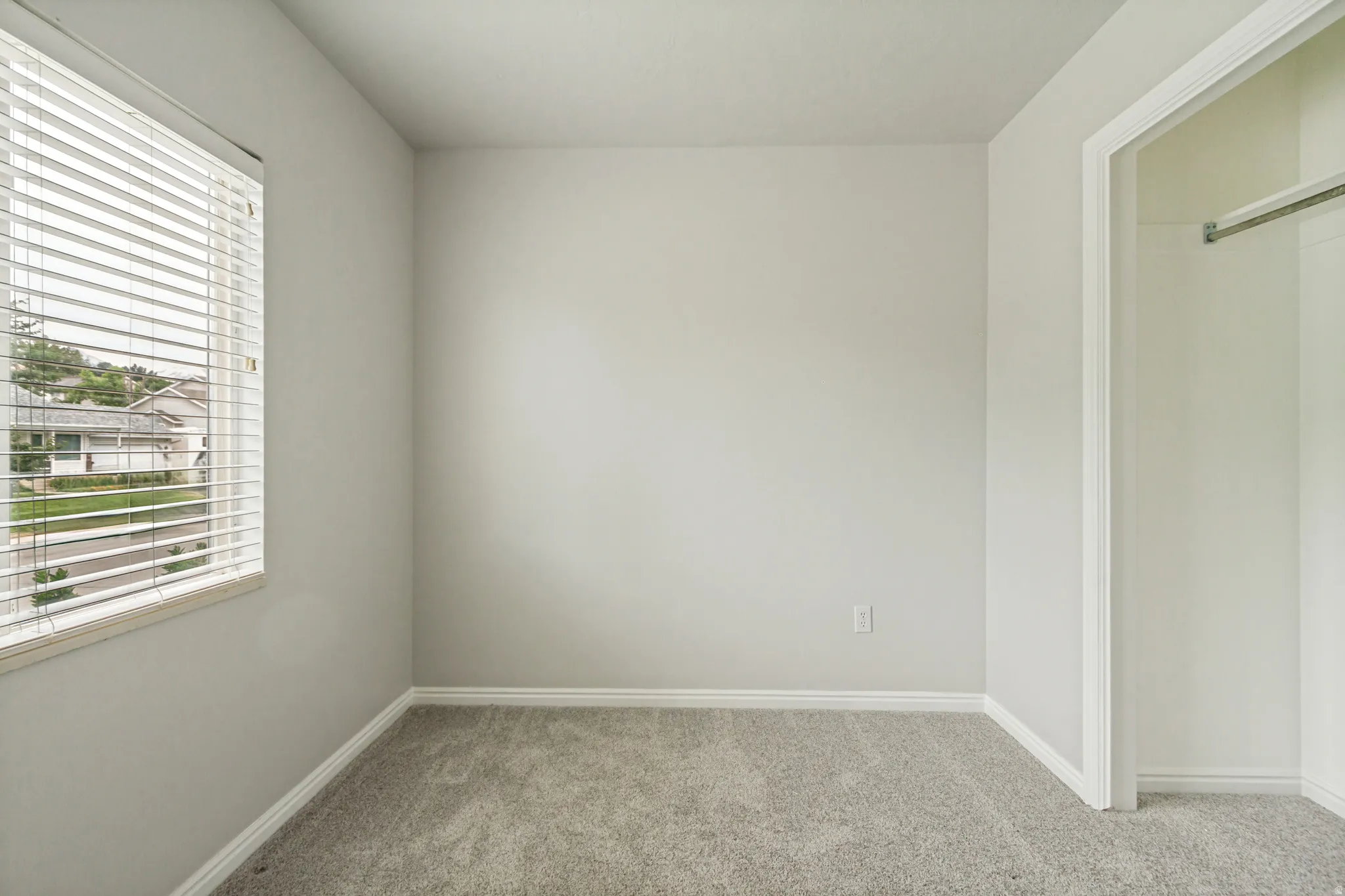 Neutral-toned interior room featuring light gray walls, gray carpeting, and white baseboards