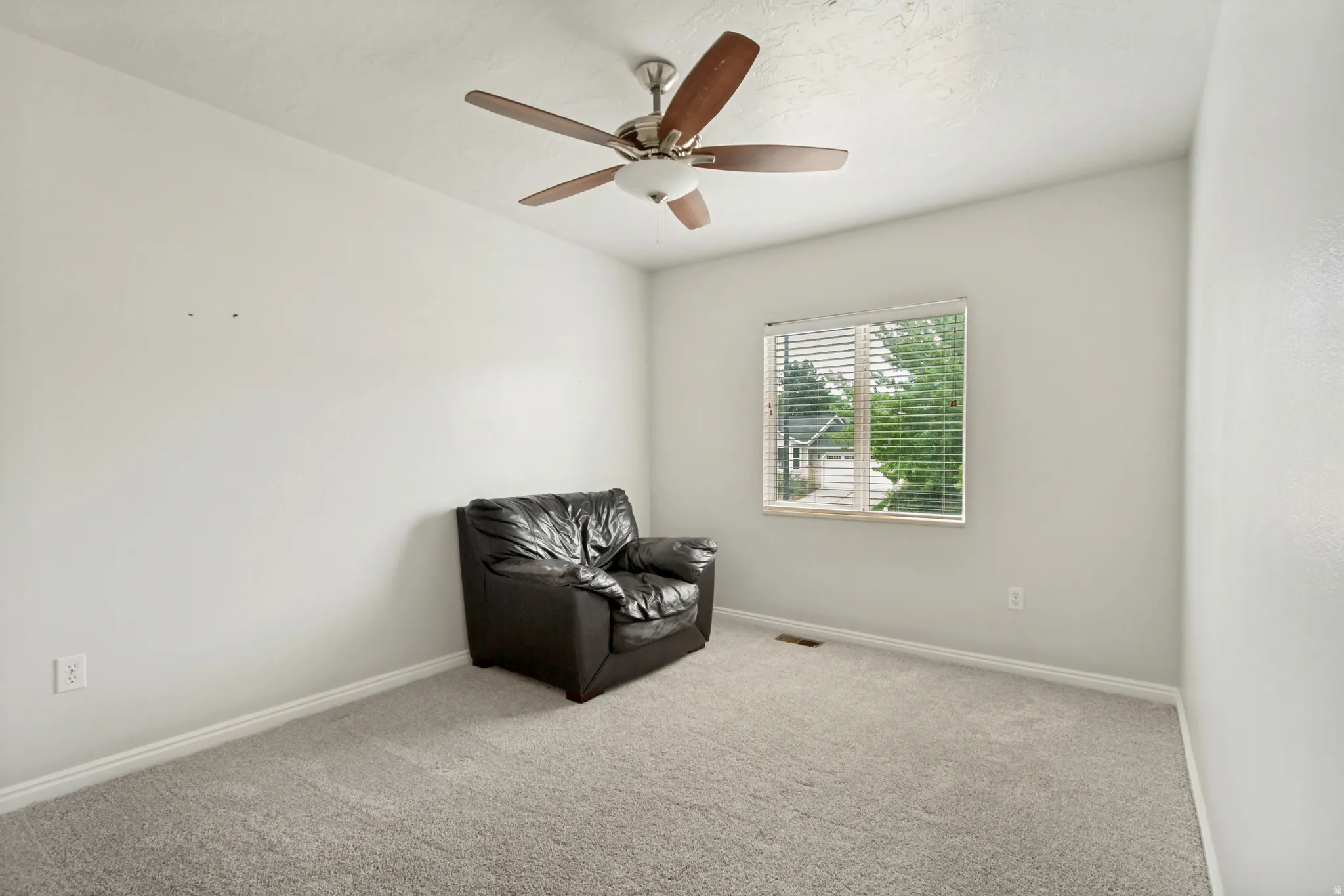 Carpeted room with a single window featuring blinds