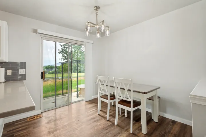 Open-concept dining area featuring wood-finish flooring, a contemporary chandelier, and a sliding glass door providing direct outdoor access